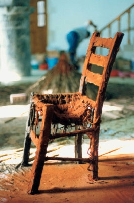 187. I. Μαυρίδης «Καρέκλα» 1998 Η παλιά καρέκλα με το επίχρισμα κόκκινου χώματος απέκτησε δραματική διάσταση και την πολυτιμότητα ενός αντικειμένου μνήμης