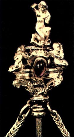 Λεπτομέρεια από το κεφάλι χρυσής περόνης. Στην κορυφή η θεά Αφροδίτη στη στάση της «Αναδυομένης»· από κάτω ερωτιδείς. Η σύνθεση αυτή διακοσμεί την άκρη της περόνης, η οποία μιμείται κορινθιακό κιονόκρανο. Στο επάνω μέρος του κιονοκράνου πολύτιμος λίθος συμπληρώνει τη διακόσμηση του εξαίρετου αυτού έργου. (Αθήνα, Μουσείο Μπενάκη)