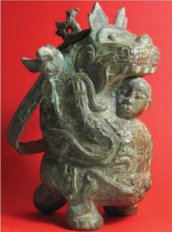 Τελετουργικό ορειχάλκινο σκεύος της δυναστείας των Σάνγκ (14ος-11ος αι. π.Χ.). Έχει τη μορφή τίγρης που προστατεύει έναν άνδρα. Όλη η επιφάνεια του σκεύους είναι καλυμμένη με ζωικά σχέδια που έχουν σχέση με τη γονιμότητα.