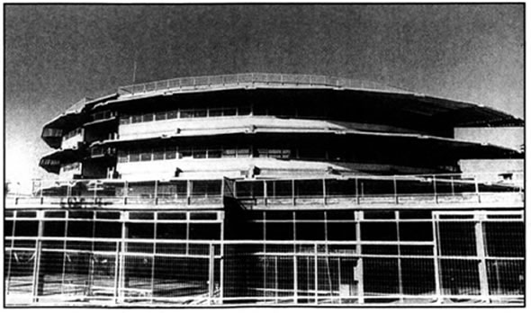 Τάκης Ζενέτος (1926-1977), Γυμνάσιο και Λύκειο, 1970-76, Άγιος Δημήτριος, Αθήνα. Ο κατ εξοχήν αρχιτέκτονας του ελληνικού μοντερνισμού, ανατρέπει με το κτίριο αυτό το καθιερωμένο μοντέλο ανάπτυξης του σχολικού χώρου. Με τη βοήθεια της τεχνολογίας και των σύγχρονων υλικών (μπετόν, μέταλλο και γυαλί) ξεπερνά το παραλληλεπίπεδο σχήμα των μοντέρνων κατασκευών, δημιουργώντας ένα κυκλικό κτίριο με ανοικτούς, ευέλικτους χώρους και πολλές δυνατότητες χρήσης και εφαρμογής των πρακτικών του σύγχρονου σχολείου.
