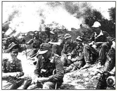 Τα Καλάβρυτα καταστράφηκαν και ο πληθυσμός τους εξοντώθηκε στις 9-13 Δεκεμβρίου 1943 από τον γερμανικό κατοχικό στρατό σε αντίποινα για αντιστασιακές ενέργειες. Στη φωτογραφία Γερμανοί στρατιώτες ξεκουράζονται,  ενώ πίσω τους τα Καλάβρυτα καίγονται.